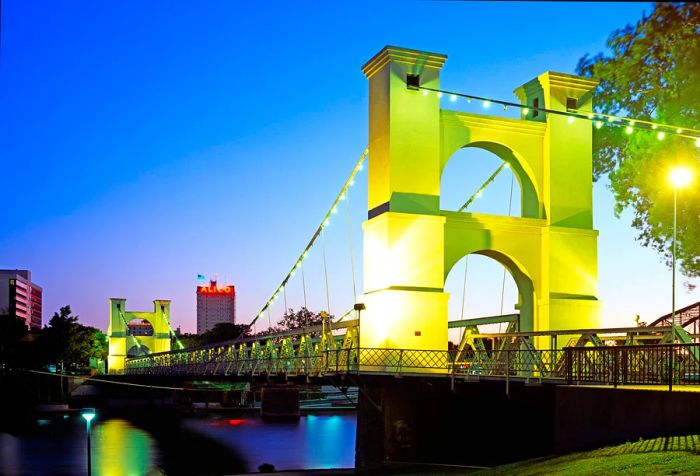 The stunning Waco Suspension Bridge, featuring its sturdy towers and intricate network of steel cables, elegantly stretches over the serene Brazos River.