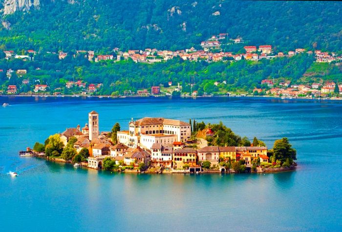 A serene island nestled in the heart of a lake, surrounded by structures and vibrant fall foliage.