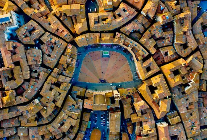 A medieval, shell-shaped town square surrounded by quaint buildings.