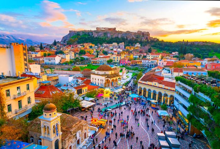 A sweeping view of a vibrant Mediterranean town bustling with pedestrians and featuring historic buildings atop a hill.