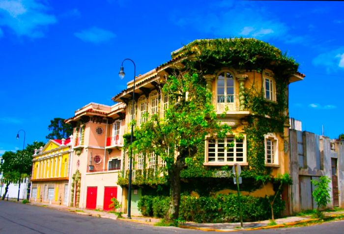 An old mansion at a crossroads draped in vibrant green vines.