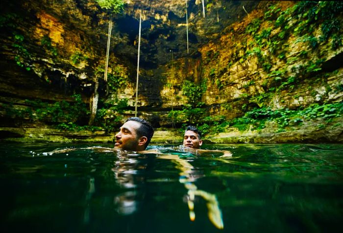 Two men enjoying the cool waters of a natural cave.