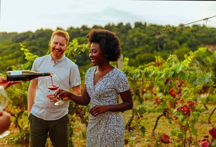 A woman enjoying a glass of wine in a vineyard.