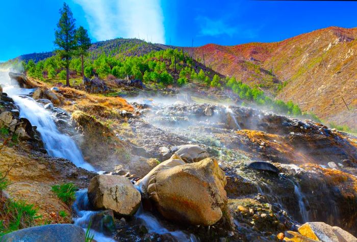 Gentle steaming waterfalls cascade down the hillside, feeding the Payette River on a partly cloudy spring morning at Kirkham Hot Springs near Lowman, Idaho.