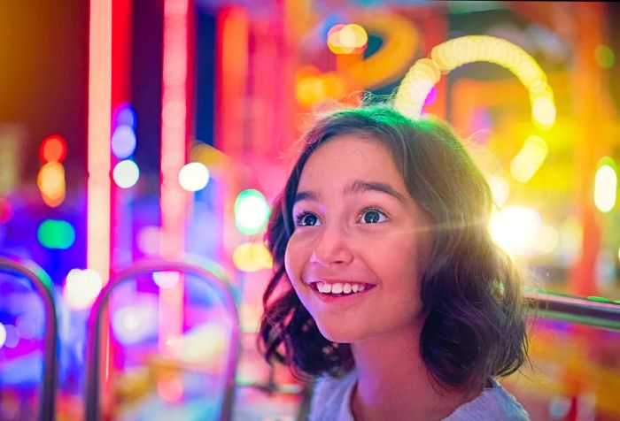 A young girl radiates joy as she explores an amusement park.