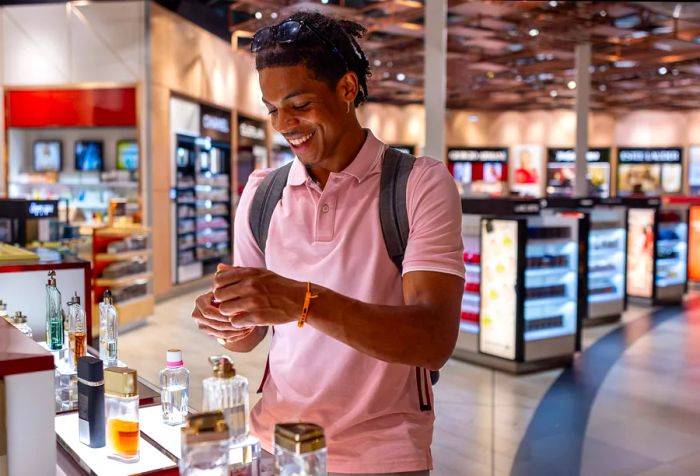 A side view of a young man in casual attire browsing a duty-free store at the airport in Toulouse, France, as he prepares for his flight. The man is testing aftershave.