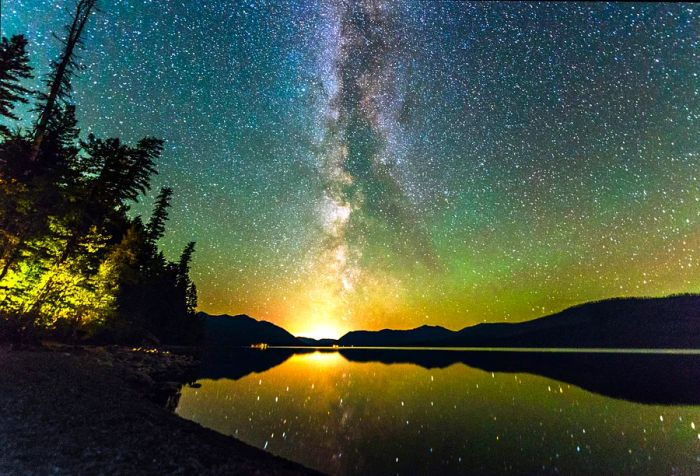 Stunning views of the Northern Lights and the Milky Way illuminating the starry night sky over the lake.