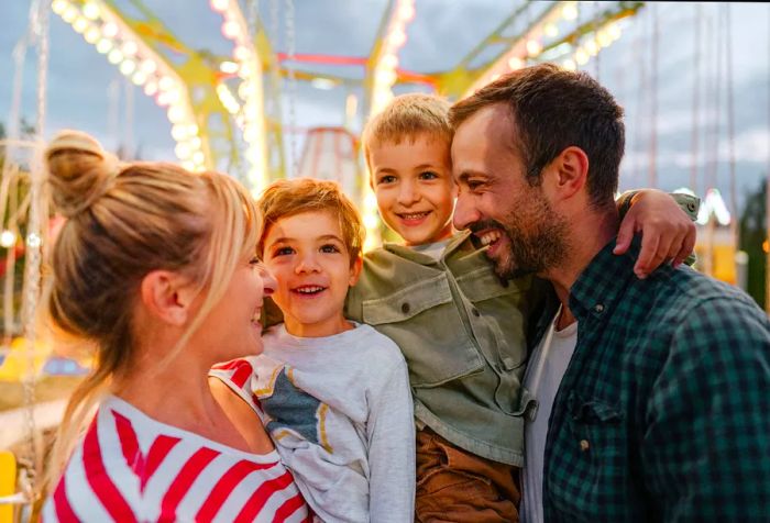 A cheerful family of four posing with a vibrant bokeh backdrop.