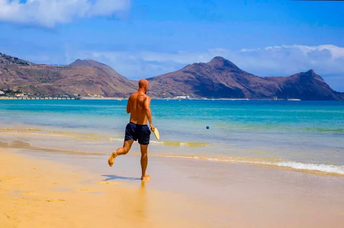 A man jogs along the sandy beach of Porto Santo in Madeira