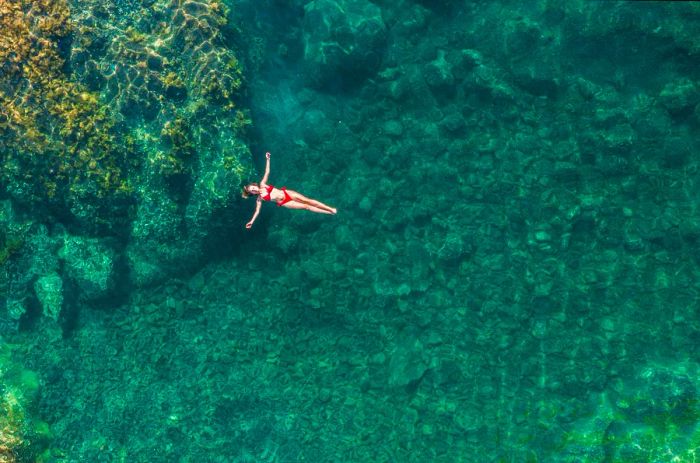 A woman enjoying the serene waters of a natural rock pool in Seixal, Madeira