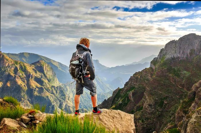 A hiker standing on the mountains of Madeira at Pico do Areeiro (Arieiro), trekking towards Pico Ruivo on a cloudy summer day.