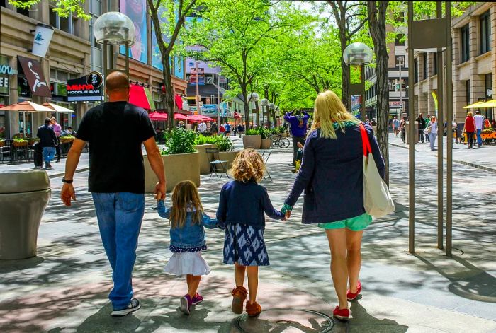 From behind, a family of four strolls through downtown Denver