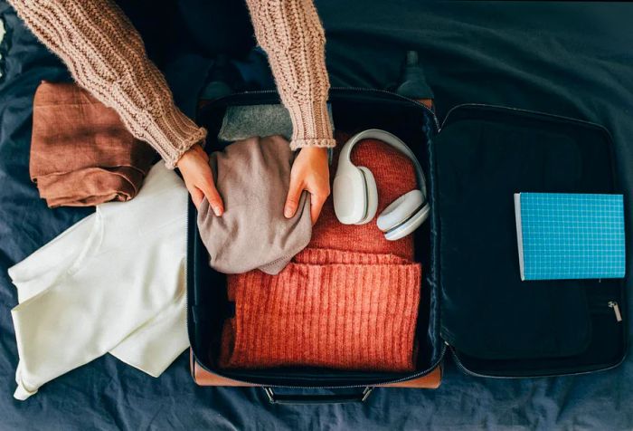 A person organizes a suitcase filled with clothes.