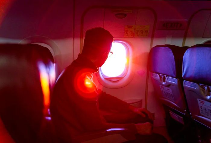 A passenger gazes out of an airplane window at a breathtaking sunset.