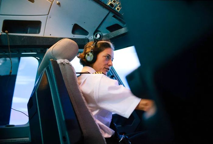 A female flight instructor seated in the cockpit while providing guidance.