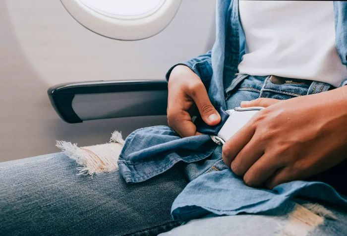 A man buckles his seatbelt while sitting in an aircraft.