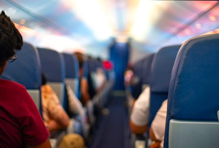 A vacant airplane aisle with passengers comfortably seated in their places.