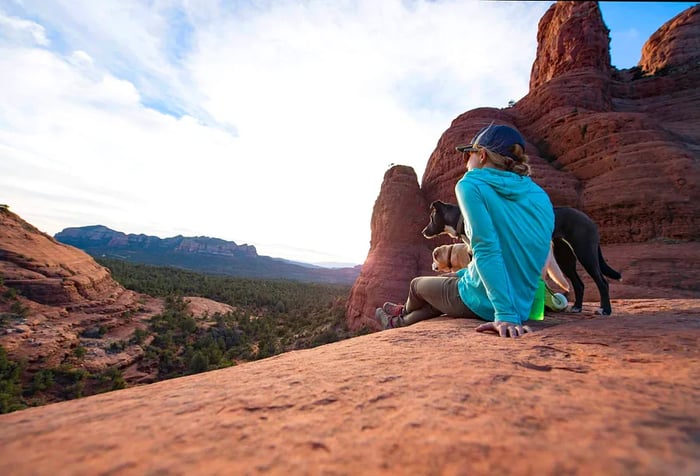 A woman and her two dogs taking a break on some rocks in Sedona