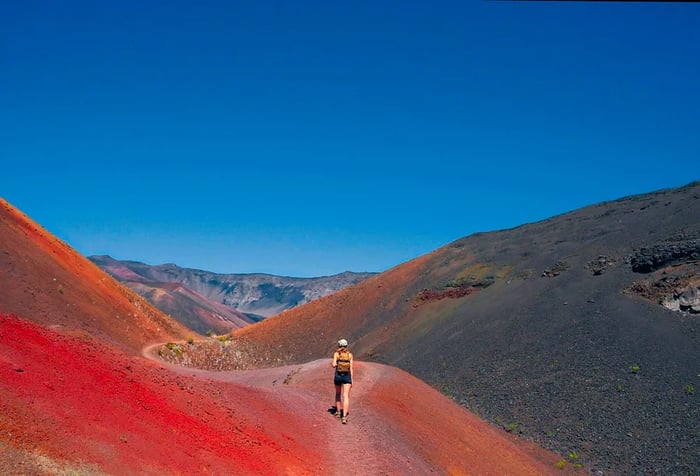 A young girl sets off on an adventure, trekking through the vividly colored sand dunes of Haleakalā National Park.