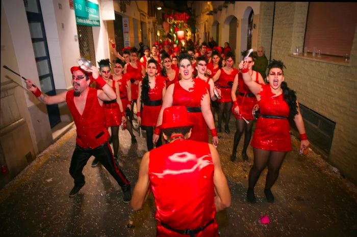 A group of men and women dressed in red and black at a Carnaval parade.