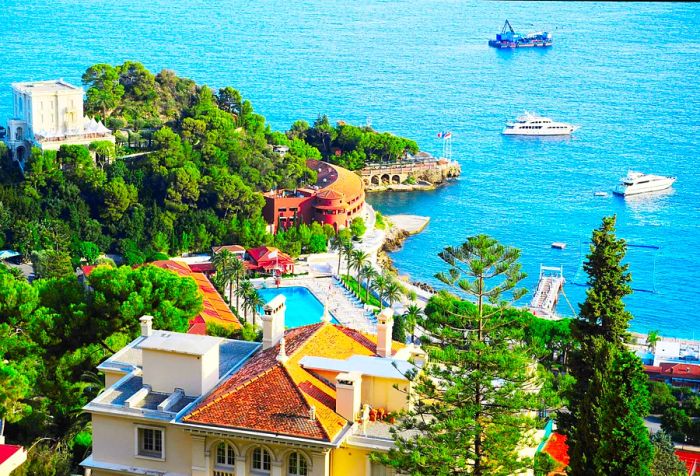 A luxurious resort featuring stunning villas that overlook boats gliding across the azure sea.