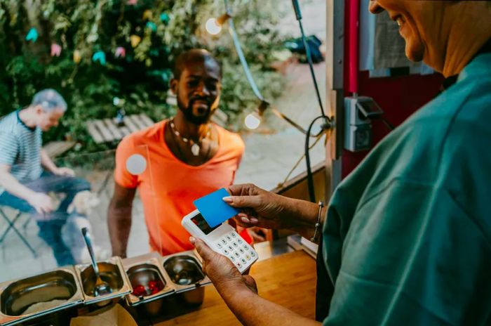 A man paying at a food truck with a credit card