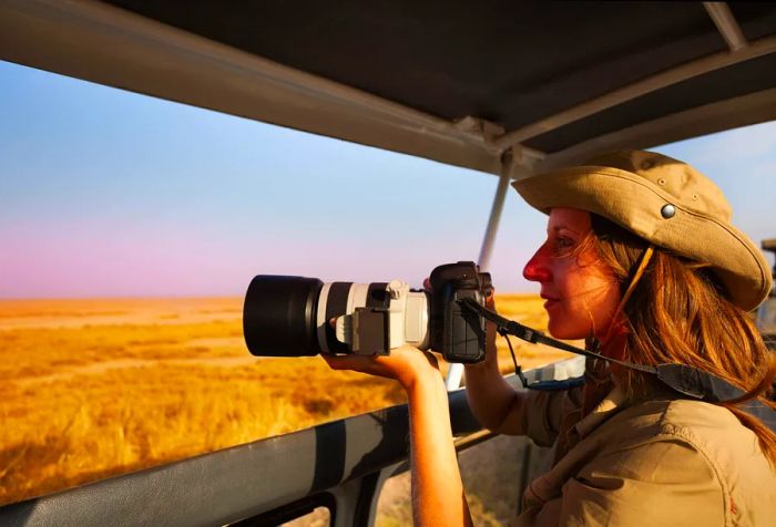 A woman takes a breathtaking photograph from a safari jeep, immersed in the vast beauty of the savannah.