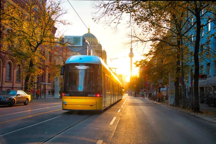 A yellow tram glides through Berlin's streets in the early morning light.