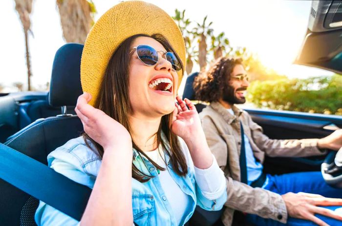 Joyful couple cruising in a convertible, soaking up the summer sun in Spain.