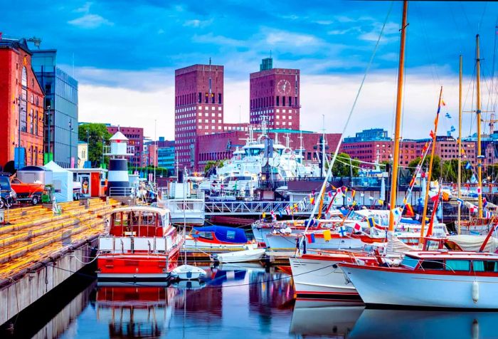 Boats adorned with colorful flags fill a harbor that is surrounded by breathtaking architecture.