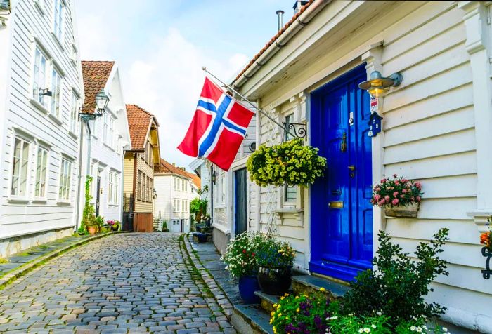 A charming old street paved with stones, featuring a blue door and decorative flower pots.