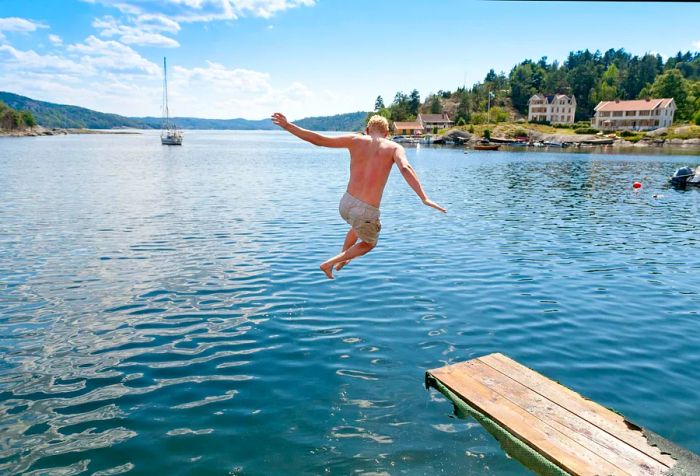 A person diving into the ocean from a wooden platform.