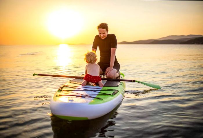 A woman and a young boy paddleboarding in the ocean.