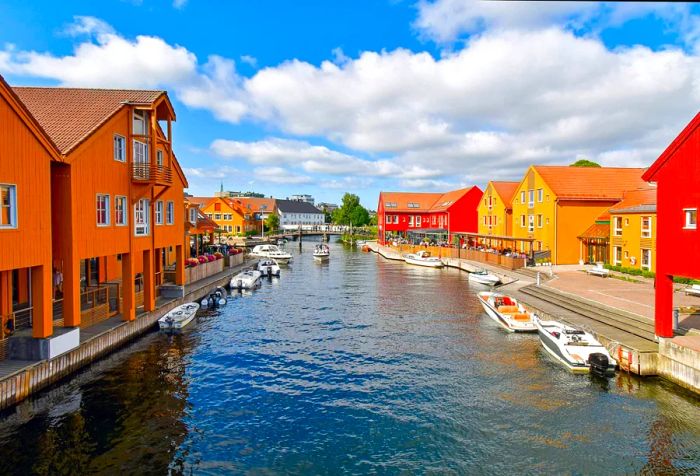 A picturesque waterfront scene showcasing boats docked next to buildings painted in vibrant shades of orange.