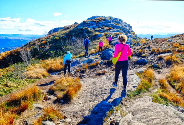 Hikers dressed in activewear navigate the rugged terrain of a mountain.