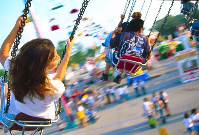 Children and adults enjoying a swing carousel at an amusement park.