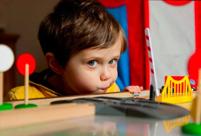 A young boy plays with toy trains.