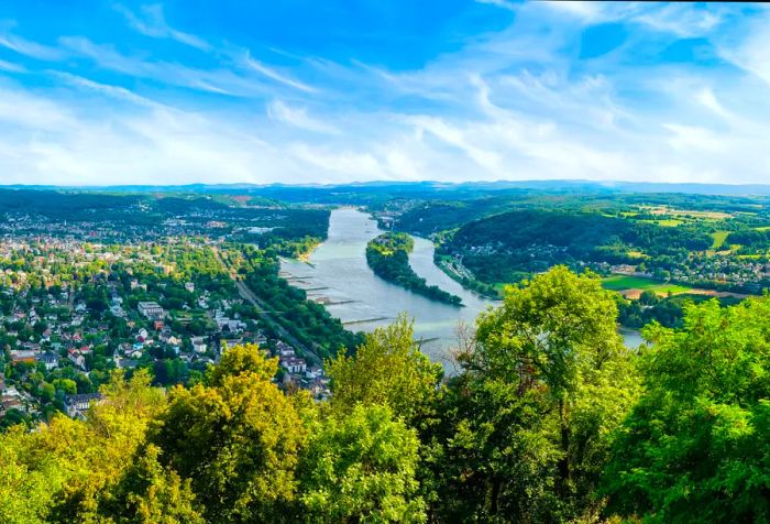 A wide river flows through a lush expanse dotted with houses and trees.