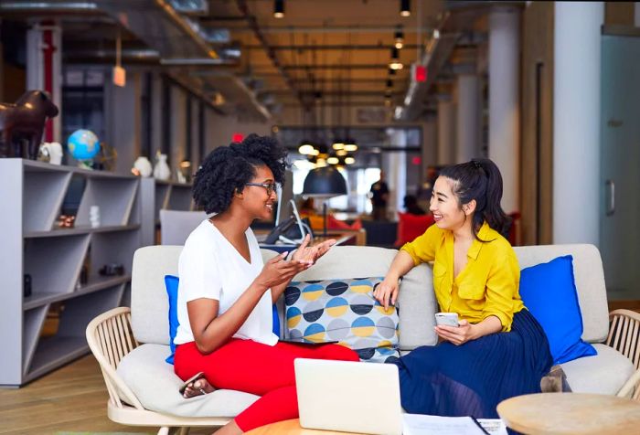 Two women are engaged in a lively conversation while seated on a couch.