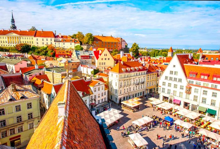 A bustling public square filled with vendor stalls, surrounded by buildings topped with red tile roofs.