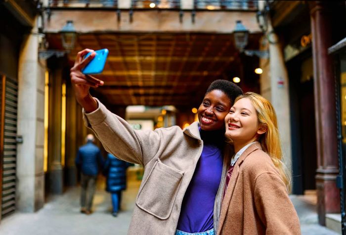 Two women standing on the street, smiling for a selfie.