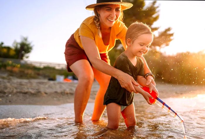 A mother and her adorable toddler enjoy playing with a fishing toy by the sea.