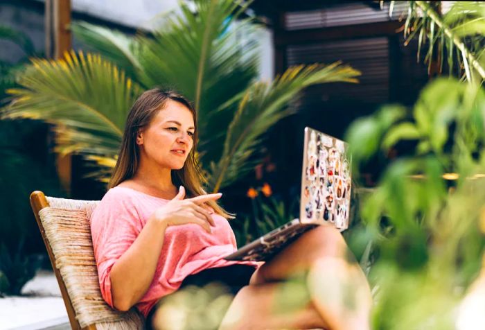 A woman working on her laptop at a beach café, blending business with leisure in a luxurious tropical setting. Engaging in online shopping, booking, and freelance work.