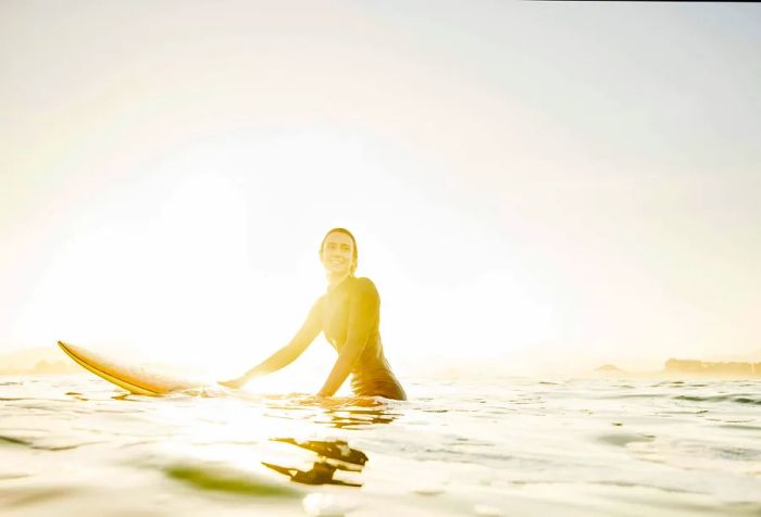 A woman relaxing on her surfboard as it drifts on the ocean.