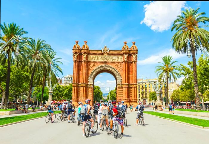 A group of people cycling in front of the Arc de Triomf in Barcelona