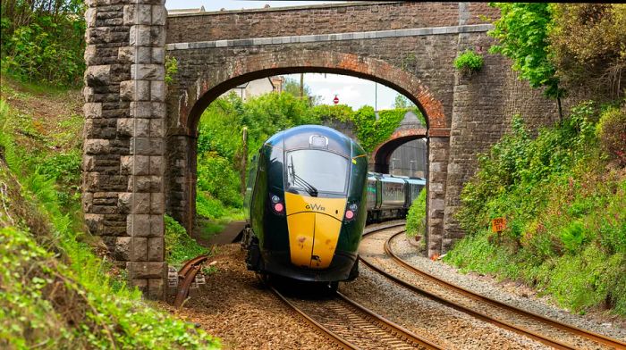 Great Western Railway train passing beneath a stone overpass in Teignmouth, Devon, England, UK