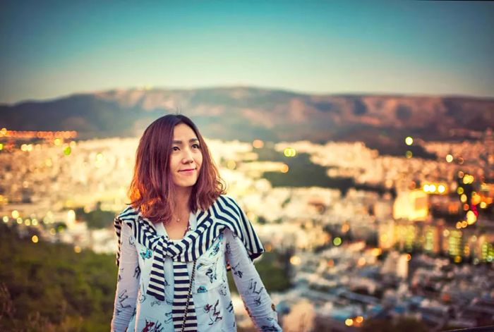 A young woman beams above the city of Athens