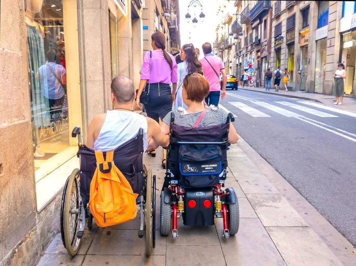 Wheelchair users in Barcelona navigate a city street together