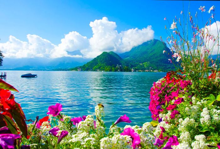 A stunning lake surrounded by vibrant flowers, with mountains in the backdrop.