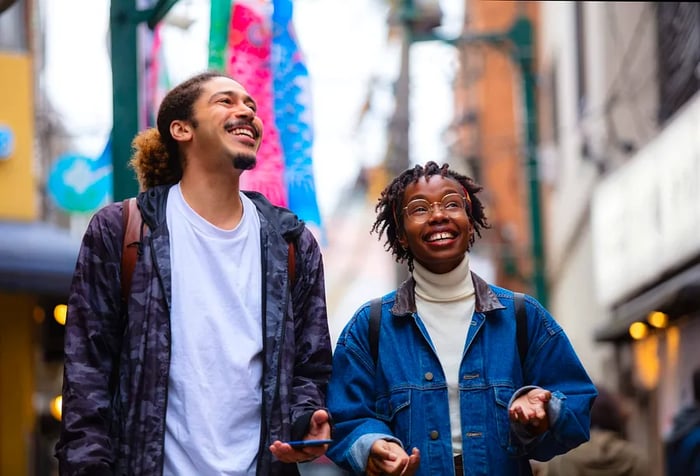 Two people share a laugh as they stroll down the street.